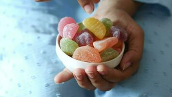 women hand pick colorful candy sweet jelly in a bowl on table video
