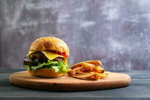 fresh tasty homemade hamburger with fresh vegetables, lettuce, tomato, cheese on a cutting board with French fries. Free space for text photo