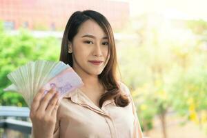 Happy Asian businesswoman smiling and holding banknote. Concept of business success and stable transactions and finance photo