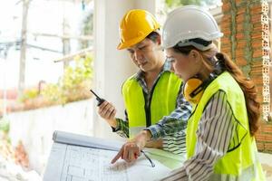 ingeniera asiática o arquitecta joven se puso un casco por seguridad y habló con un contratista en un proyecto de construcción de fábrica, concepto de trabajo en equipo, concepto de liderazgo. foto