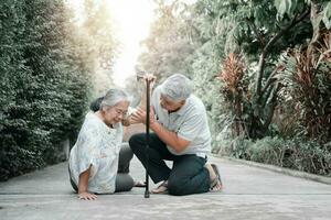 Asian senior woman falling down on lying floor at home after Stumbled at the doorstep and Crying in pain and her husband came to help support. Concept of old elderly insurance and health care photo