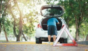 Asian man find tools in the car for car repair after a car breakdown on street. Concept of vehicle engine problem or accident and emergency help from Professional mechanic photo