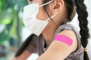 Close-up of medicinal plaster after vaccinated in shoulder of Asian girl kids in hospital. Pediatrician makes vaccination for kids. Vaccination, immunization, disease prevention concept. photo