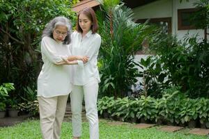 una anciana asiática y caminando en el patio trasero con su hija. concepto de jubilación feliz con el cuidado de un cuidador y ahorros y seguro de salud para personas mayores, familia feliz foto