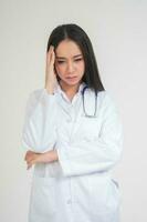 Young Asian woman doctor standing and holding hands in the head Due to headache, she looks unhappy and tired because of overwork, Concept of stressed and doctor liability, Dealing with frustrated photo
