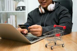 A Man holding credit card and using laptop for payment online for purchase after order products via the internet. The concept of technology for e-commerce electronic commerce photo