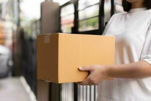 Postal service sending paper cardboard box to customer in front of a house outdoor. Shipping service arrival and send to customer address. photo