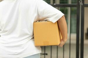 Postal service sending paper cardboard box to customer in front of a house outdoor. Shipping service arrival and send to customer address. photo