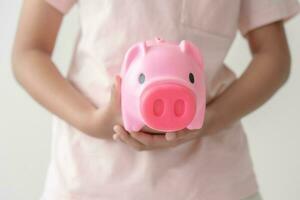 Kid holding her saving coins jar concept of savings money for future education school admission fee. Little daughter learn to save money. photo