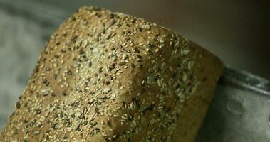 Close up View Of A Brown Loaf Bread With Sesame Seeds Rest On A Baking Tray In The Bakery. - Pan Down, slow motion video