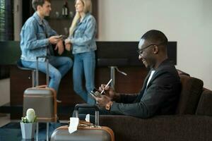 Businessman working on tablet PC while waiting for his flight at airport lounge photo