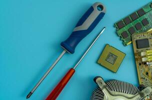 Computer chip of PC motherboard and screwdriver at repair workshop. Top view CPU chipset on blue background. Electronic components. Computer hardware. Upgrade computer processor chip. Chip shortage. photo