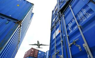 Airplane flying above container logistic. Cargo and shipping business. Container ship for import and export logistic. Logistic industry from port to port. Container at harbor for truck transport. photo