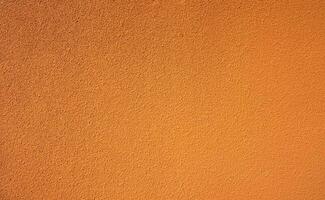 Orange rough concrete wall texture background. Empty orange concrete wall abstract background. Full frame orange cement wall texture background. Blank grain stucco wall. Orange concrete material. photo