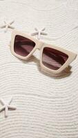 Sunglasses on sand, summer beach accessories photo