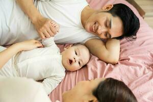 Asian family image with baby lying in bed photo