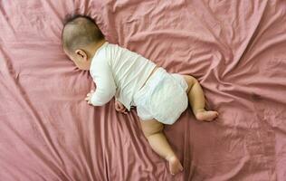 image of a newborn baby lying on a pink bed photo