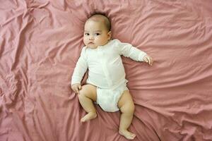 image of a newborn baby lying on a pink bed photo