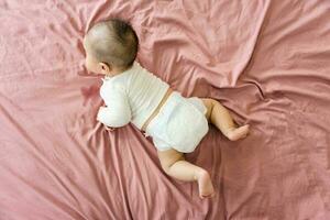 image of a newborn baby lying on a pink bed photo