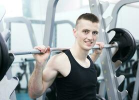 Athletic man with a dumbells in gym photo