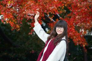 joven chino mujer en acción con otoño hojas foto