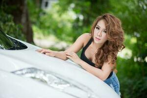 Sexy girl in black vest is posing on hood car photo