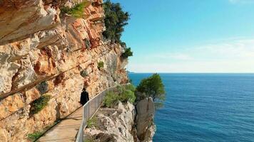 Antenne Drohne Aussicht von ein Person Gehen auf ein schön sonnig Küsten Bereich. Ferien und Ferien Zeit. Felsen und Klippen Nächster zu das Meer. Sommer. entspannen Konzept. Strand. video