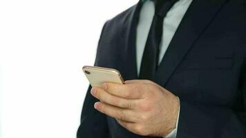 Man in a suit standing in front of white background making transactions on a phone with a credit card, an image of a businessman using his online card video