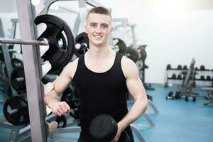 Athletic man with a dumbells in gym photo