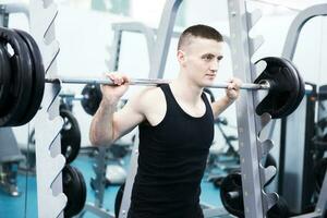 atlético hombre con un mancuernas en gimnasio foto