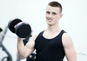 Athletic man with a dumbells in gym photo