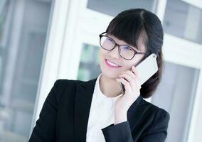 Modern business woman in the office, talking on phone photo