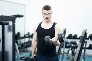 atlético hombre con un mancuernas en gimnasio foto