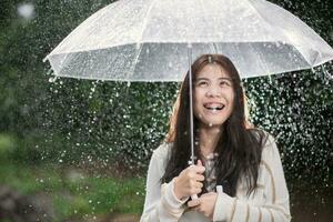 Happy Asian girl with transparent umbrella among the rain photo