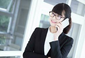 Modern business woman in the office, talking on phone photo