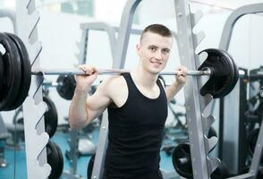 Athletic man with a dumbells in gym photo