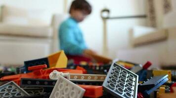 niño obras de teatro juegos y haciendo creativo construye con pequeño el plastico Lego piezas, chico jugando con vistoso Lego piezas de diferente tamaños, selectivo atención video