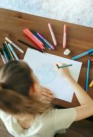 Child girl drawing with colorful pencils photo