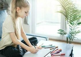 Child girl drawing with colorful pencils photo