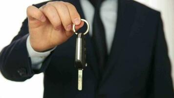 Man in a suit standing in front of the white background showing the ignition and the way he turns it on to the camera video