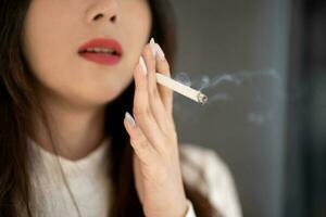 joven asiático mujer de fumar. el fármaco es perjudicial a el respiratorio sistema. foto