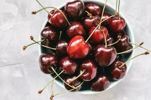 Fresh ripe cherries in a bowl on a gray background photo