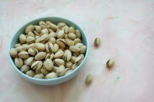 Pistachio in shell in bowl on pink background photo