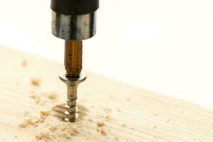 Screwdriver tightening a screw in a wood piece. Copy space photo