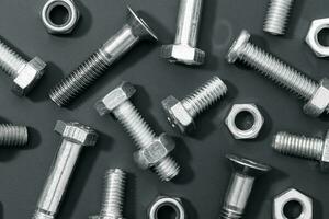 Creative background of a variety of metallic nuts and bolts on black background. Full frame photo