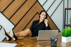 A female businessman procrastinates in the workplace. A business woman has her feet up on the table photo