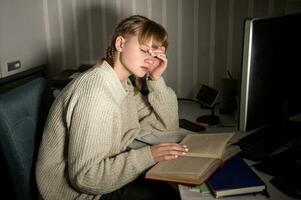 A teenage girl at home is preparing for exams at night. overtime, overwork. photo