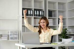 Beautiful young teen asian business women holding computer laptop with hands up in winner is gesture, Happy to be successful celebrating achievement success photo