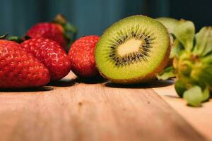 Closeup shot of colorful fruits kivi and strawberry on wooden table photo