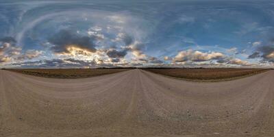 evening 360 hdri panorama on gravel road with clouds on blue sky before sunset in equirectangular spherical seamless projection, use as sky replacement in drone panoramas, game development as sky dome photo